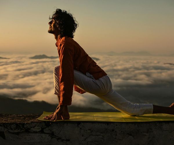 Silhouette of a person in a powerful yoga pose against a sunrise.